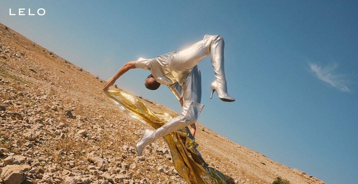 LELO woman doing back flip in metallic grey clothes