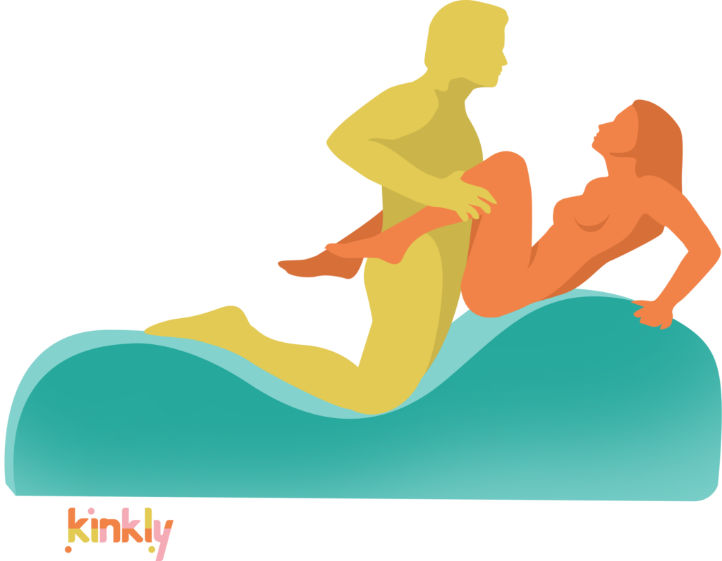 The penetrating partner kneels at the lowest point of the sex chaise, facing the receiving partner. The receiving partner is leaning backwards while seated with their butt and lower back on the sex chaise. They're bracing with their arms. | Kinkly