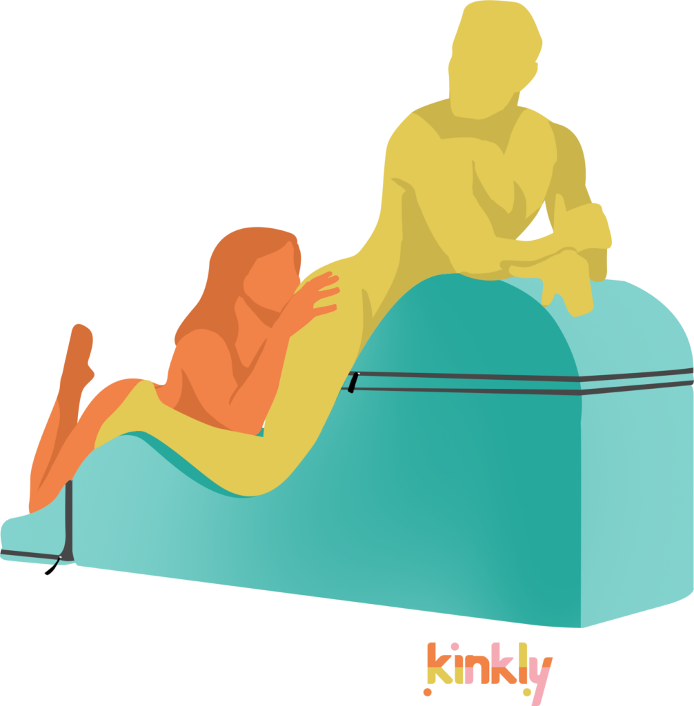 Indulgent Snacking Rimming oral sex position. The receiving partner is lying face down with their knees at the lowest point of the sex chaise and their abdomen supported by the tallest hill of the sex chaise. The giving partner is kneeling at the edge of the sex chaise, kneeling on a sex chaise pillow, to give rimming to the receiving partner's butt that's at face height. | Kinkly