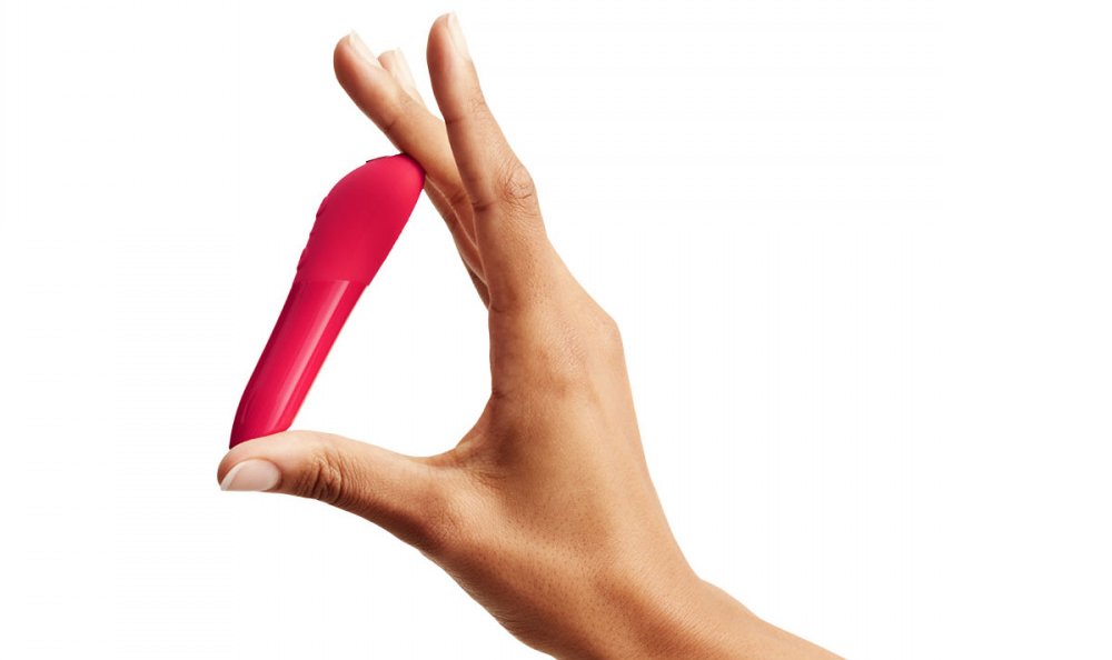 A hand holding the We-Vibe Tango X to show the small size of the pink bullet vibrator | Kinkly Shop