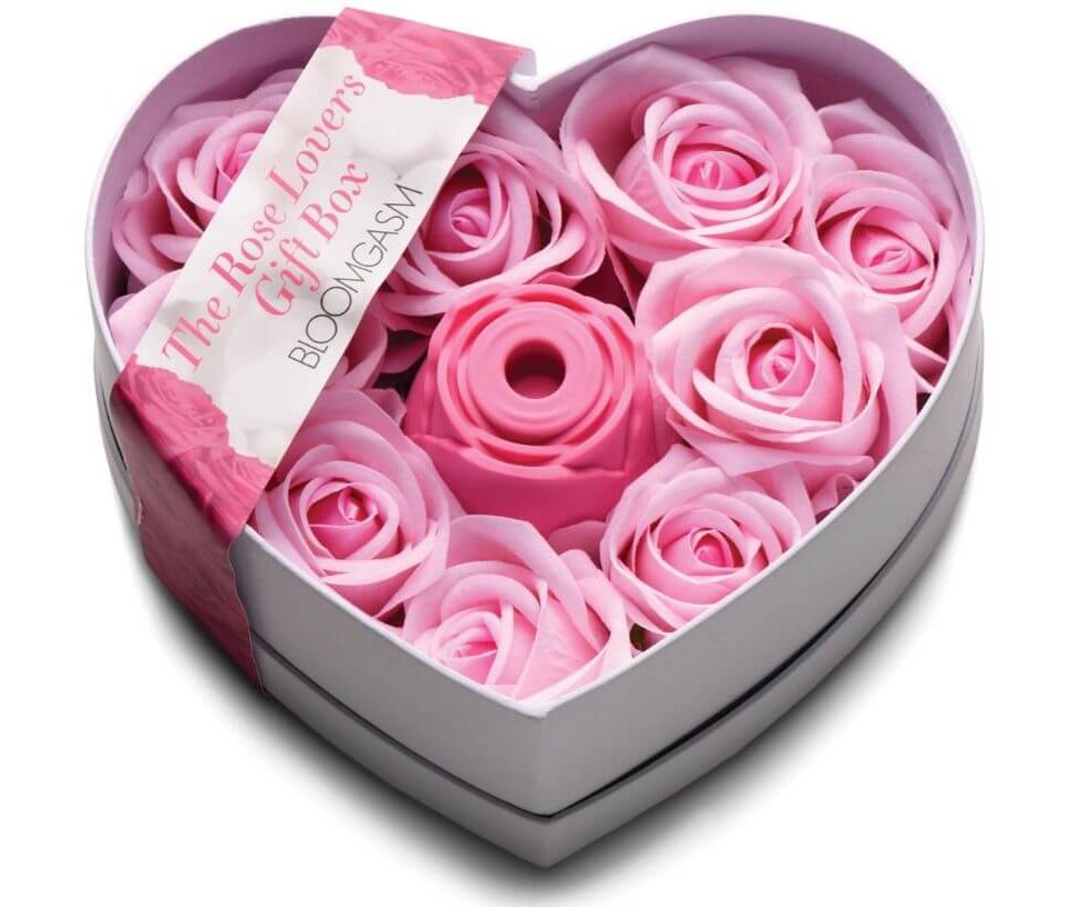 The packaging for the XR Bloomgasm Rose Lover's Gift Box. It's a heart-shaped box. In the middle of the open box, there's the Bloomgasm Rose vibrator. Surrounding this single vibrator is a bunch of faux, color-matched pink roses to make it look like someone is being gifted a full box of roses - only one of them is a vibrator. | Kinkly Shop