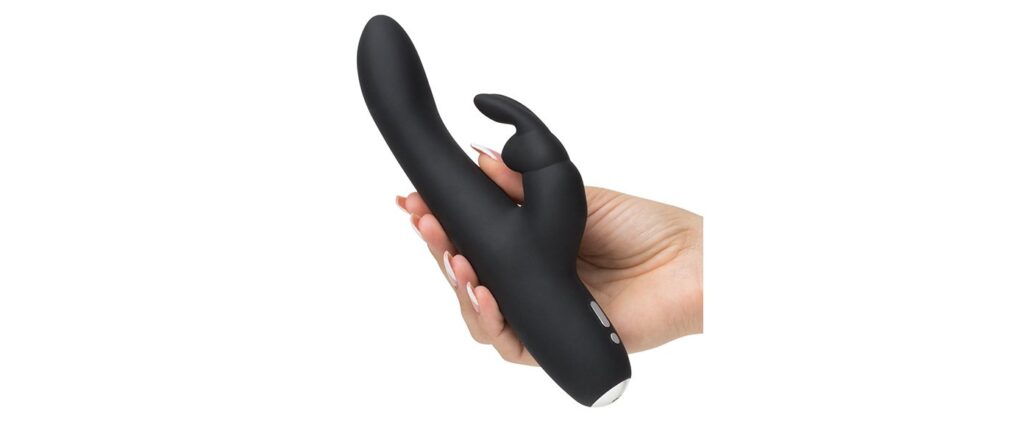 The Greedy Girl Rechargeable Slimline is being held in someone's hand. The shaft looks surprisingly slender compared to most rabbit vibrators. The base of the vibrator has a rounded base. | Kinkly Shop