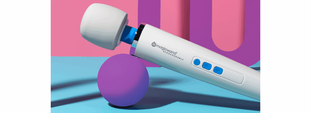 Square image of the Vibratex Magic Wand Rechargeable. The massager is tilted upwards with the handle balancing precariously on a purple ball. The pink background contrasts with the blue and white of the wand massager. Purple, contrasting, geometric shapes are in the background of the image.  | Kinkly Shop