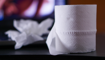 Roll of toilet paper and crumpled up tissues on a nightstand.